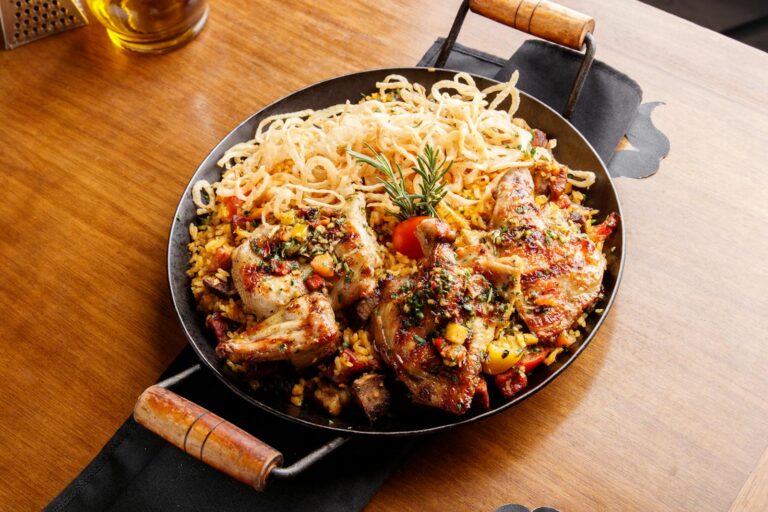 A skillet with chicken and noodles on top of a table